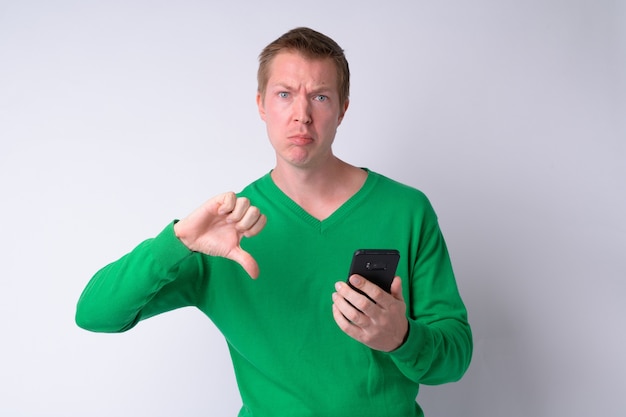 Portrait of young sad man using phone and giving thumbs down