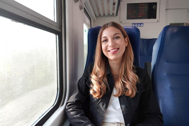 Portrait of young satisfied woman traveling with public transport sitting relaxed thoughtless Looking at camera