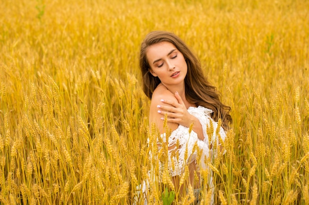 Portrait of a young sexy blonde woman on a background of golden wheat field summer outdoors