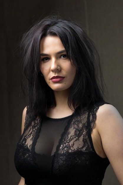 Portrait of a young sexy brunette girl in a lace top in dramatic tones. Vintage photo.