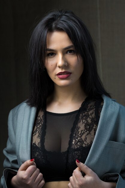 Portrait of a young sexy brunette girl in a lace top in dramatic tones.