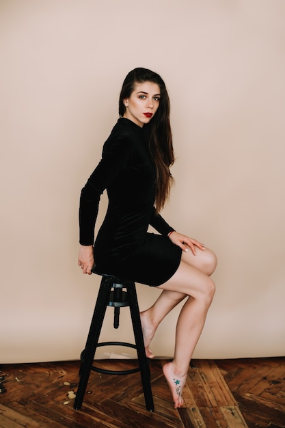 Portrait of a young sexy woman in a black dress indoors