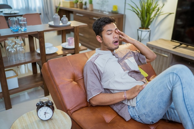 Photo portrait of young sleeping muslim man in the bed turning the alarm off