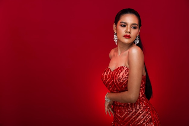 Portrait of Young Slim Idian Woman wears white sequin Evening Ball Gown long dress, Beautiful india Girl poses half body feeling emotion happy smile, red fabric fluttering background