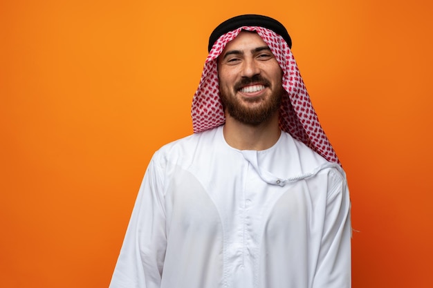 Portrait of young smiling Arab man on orange background