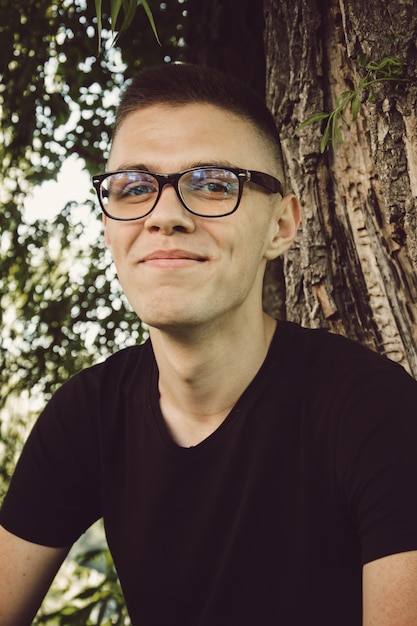 Portrait of young and smiling cute man with glasses in park