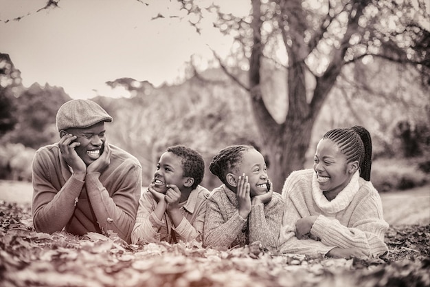 Портрет молодой улыбающейся семьи, лежащей в листьях