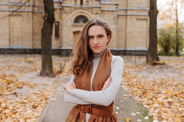 Portrait of young smiling girl in a gray dress at autumn park