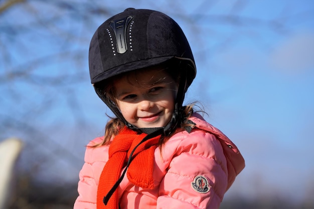 Портрет юной улыбающейся девушки в дрессировочном шлеме