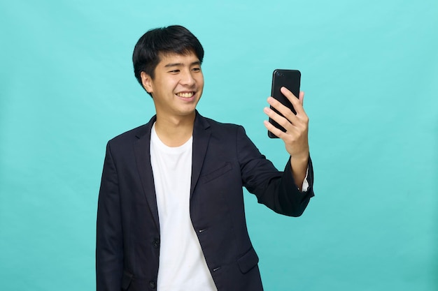 Portrait of a Young smiling handsome Asian man in a semiformal suit using a mobile phone