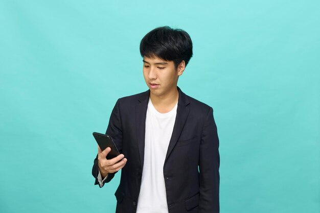 Portrait of a Young smiling handsome Asian man in a semiformal suit using a mobile phone