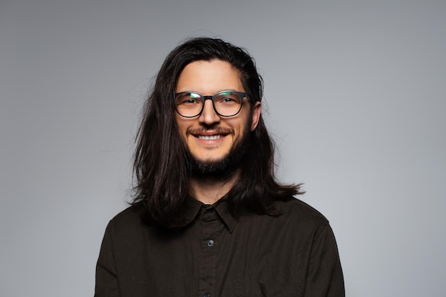 Portrait of young smiling handsome man with long hair and glasses