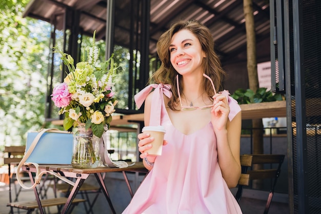 コーヒーを飲みながらカフェに座っている若い笑顔の幸せなきれいな女性の肖像画