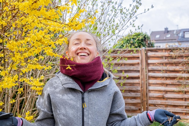 Foto ritratto di una giovane donna felice e sorridente in piedi in un giardino primaverile