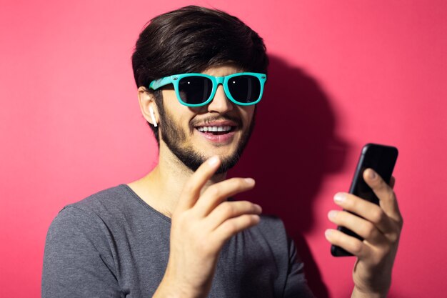Portrait of young smiling man using smartphone and wireless earphones