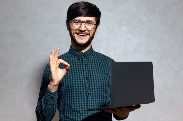 Ritratto di giovane uomo sorridente con il portatile in mano