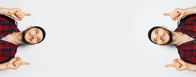 Портрет молодых улыбающихся мужчин, указывающих пальцами на пространство для копирования на белом фоне в красной клетчатой рубашке и черной ленте Панорамный вид баннера