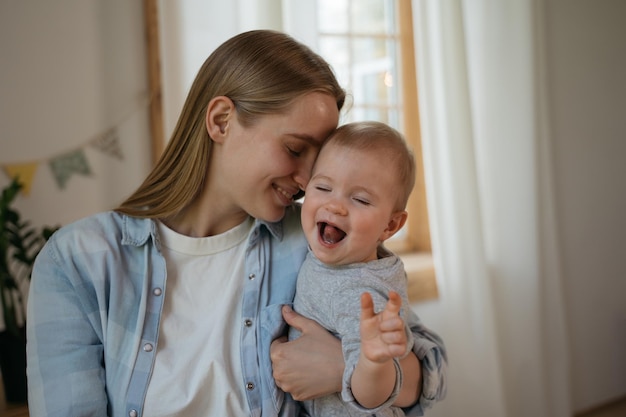 Ritratto di giovane madre sorridente che tiene e abbraccia il suo bambino felicità amore e concetto di cura