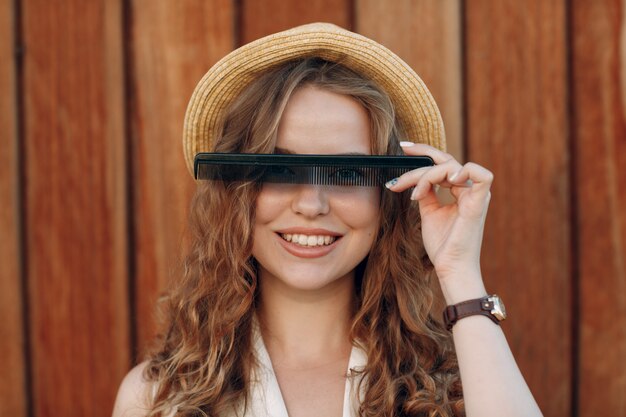 Portrait of young smiling positive female with curly hair with comb