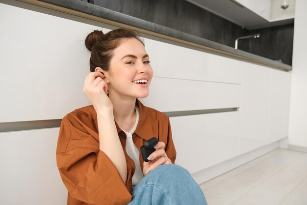 Portrait of young smiling woman girl puts on her black wireless headphones listens to music in