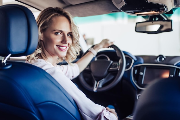 Portrait of young smiling woman sitting in the car and looking at the camera