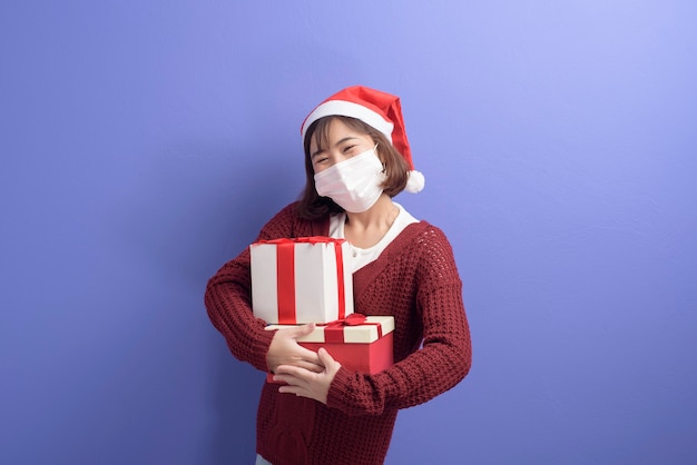 Portrait of young smiling woman in surgical mask wearing red Santa Claus hat isolated