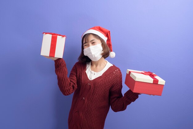 Portrait of young smiling woman in surgical mask wearing red Santa Claus hat isolated