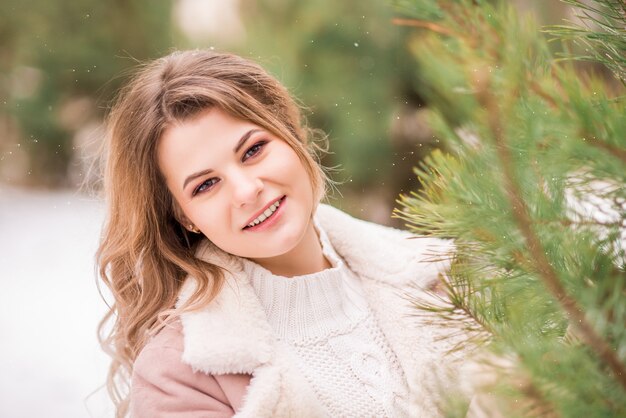 Portrait of a young smiling woman in a winter forest.