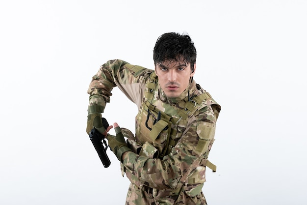 Portrait of young soldier in camouflage on a white wall