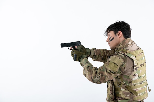 Photo portrait of young soldier in camouflage with gun studio shot white wall