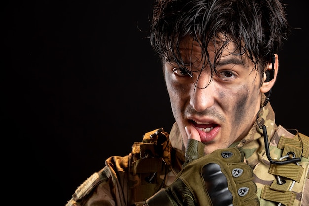 Portrait of young soldier in uniform on a dark wall