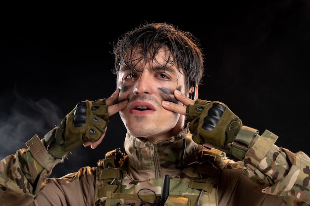 Portrait of young soldier in uniform on the dark wall