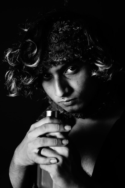 Portrait of a young South Asian male model with a scarf on his head smelling a cologne