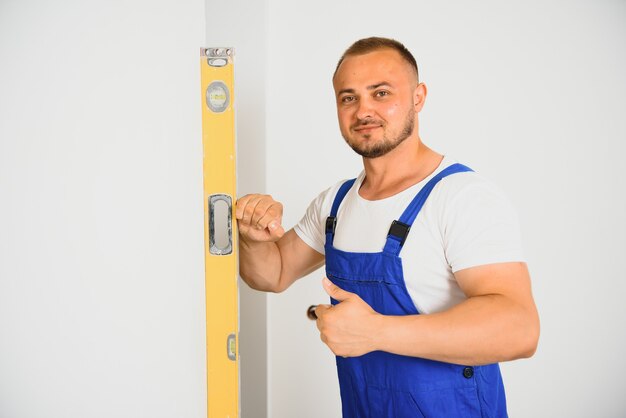 Portrait of young specialist making wall plane in new building