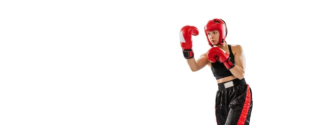 白いスタジオの背景の上に分離された特別な制服でキックボクシングを訓練する若いスポーツ少女の肖像画