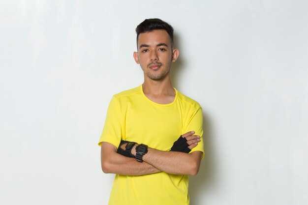 Портрет молодой спортивный мужчина, одетый в желтую футболку на белом фоне