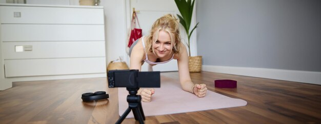 Foto ritratto di un giovane istruttore di fitness vlogger sportivo in piedi su una tavola su un tappetino da yoga di gomma