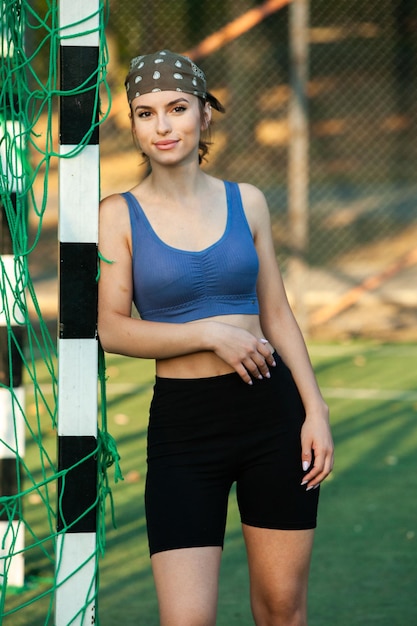 Портрет молодой спортивной женщины в спортивной одежде, стоящей на игровой площадке