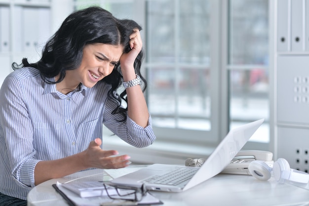 Portrait of a young stressed woman using laptop