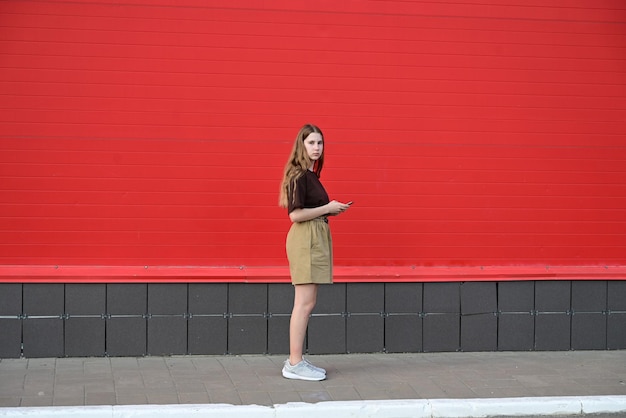 Portrait of a young student reading a message on a mobile phone a stylish pretty girl chatting on a mobile phone while walking down the streetsocial disorder disorder technology diseasedependent