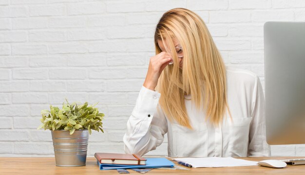 Portrait of young student sitting on her desk doing tasks laughing and having fun.