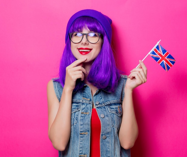 Portrait of young style hipster girl with purple hair and United Kingdom flag on pink background