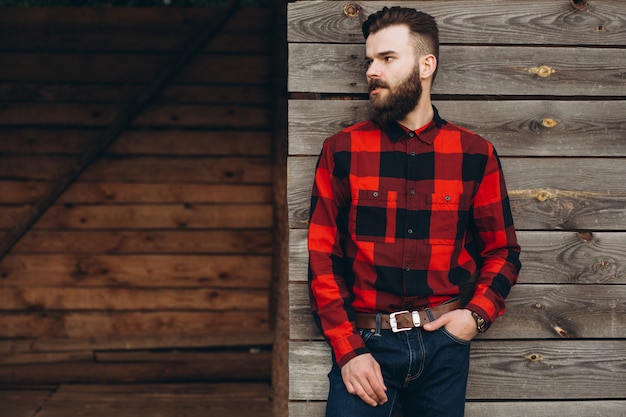 Photo portrait of a young stylish bearded man dressed up in jeans and a true worker black by red shirt.