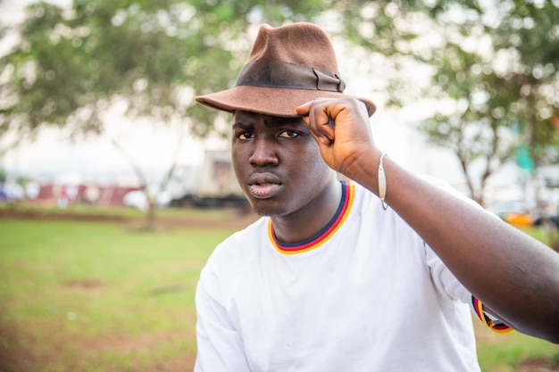 Foto ritratto di un giovane ragazzo africano elegante e serio che tocca il suo cappello