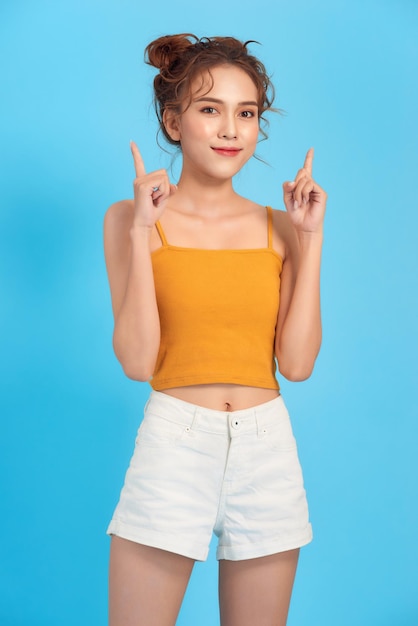 Portrait of young stylish woman in croptop pointing fingers up smiling and look amused interested found product show promo