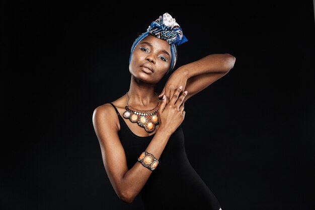 Portrait of a young stylish woman posing and looking at front in studio isolated on the black wall