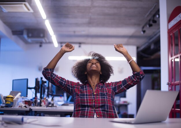 Photo portrait of a young successful african american beautiful woman who enjoys spending a quality and joyful time while working in a large modern office