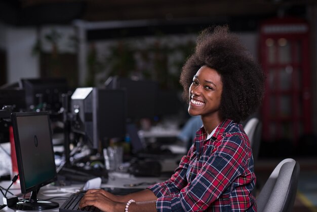 portrait of a young successful African American woman who enjoys while working in a large modern office