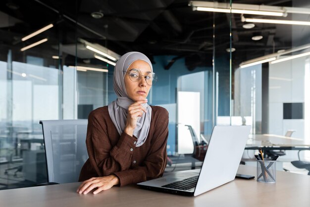 테이블에 사무실에 앉아 hijab에서 젊은 성공적인 아랍 사업가의 초상화와