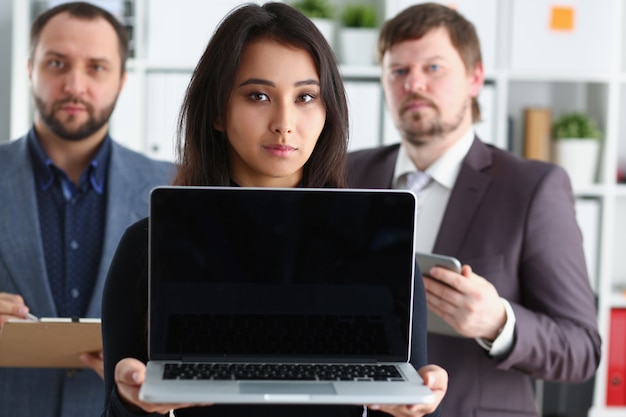 Portrait of young successful businesslady hold laptop and two businessmen in office